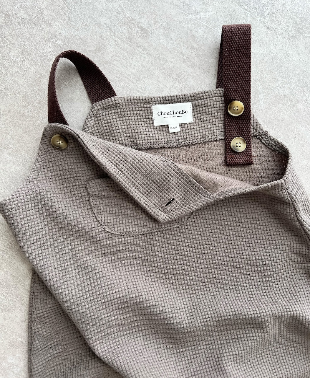 Hipster baby boy clothes: details of brown sleeveless overall with easy snap buttons.