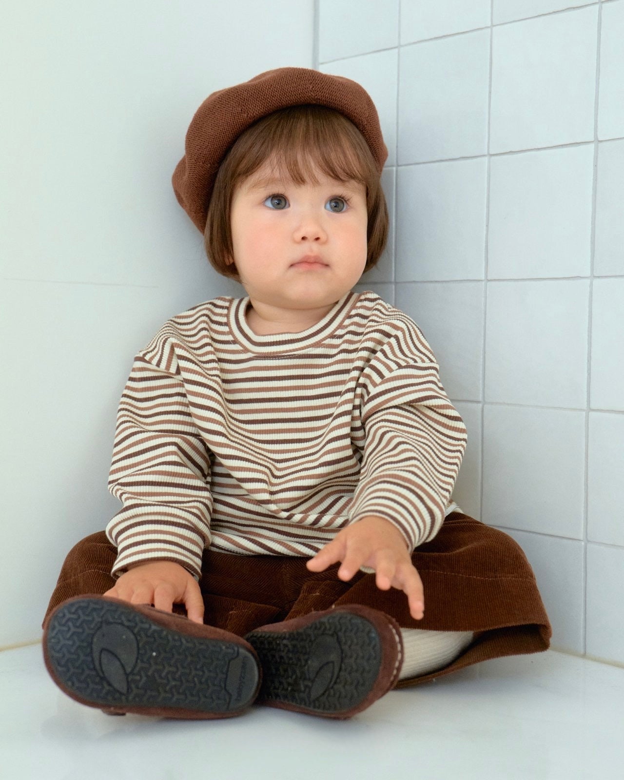 baby wearing a striped shirt and brown hat