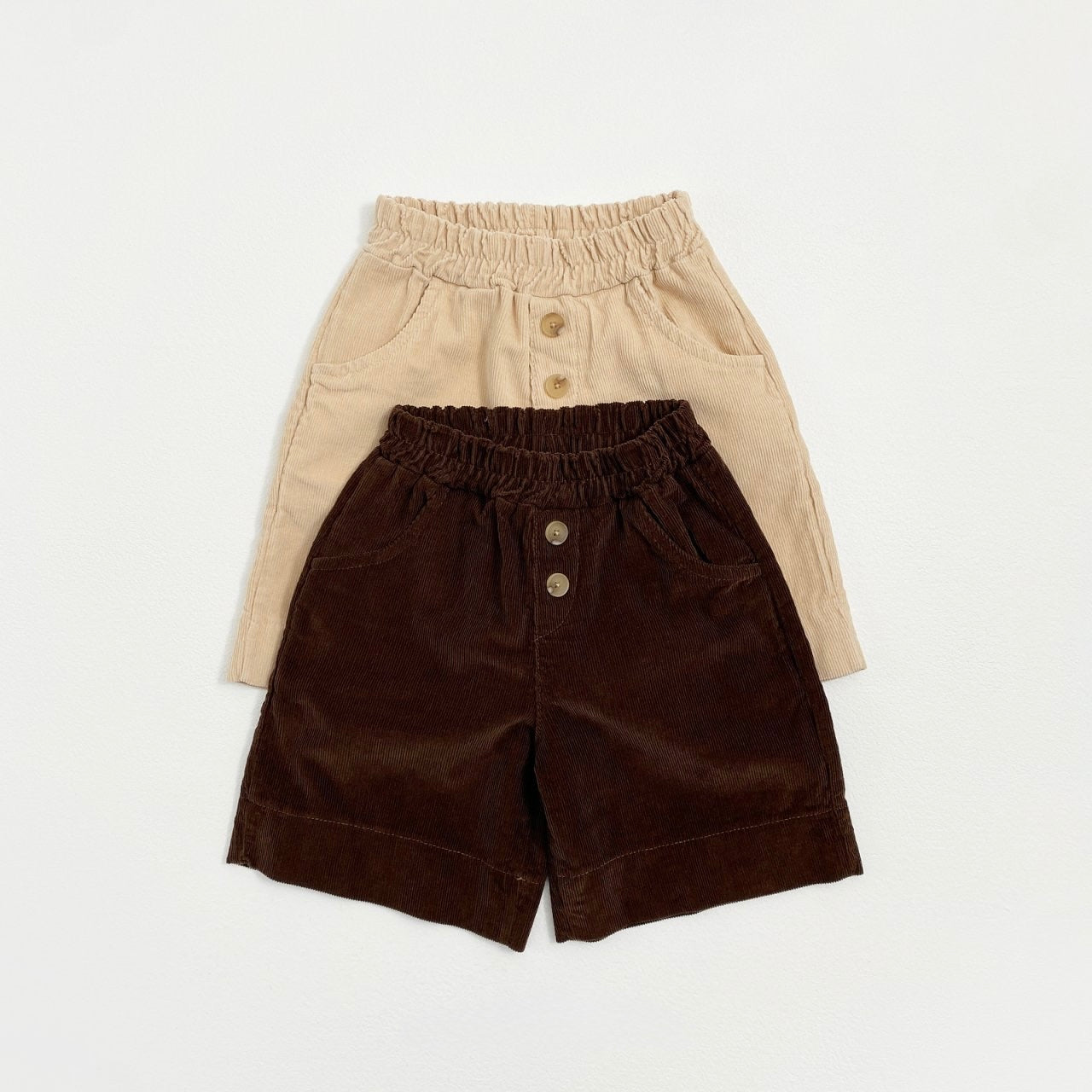 Two pairs of baby toddler corduroy pants, one beige and one brown