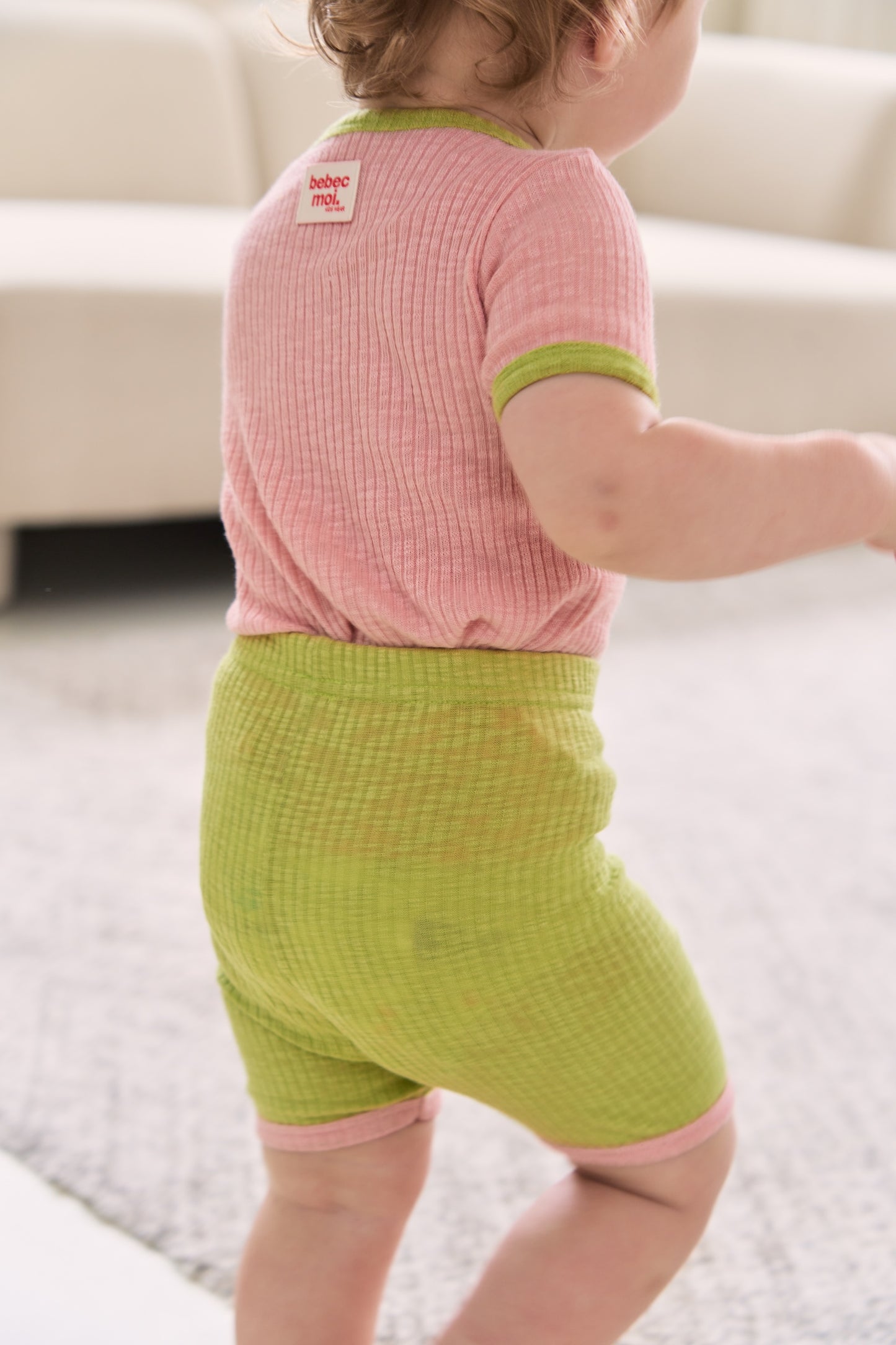 Unique baby clothes set with a mix of earthy and pastel tops and pants in green and pink from back