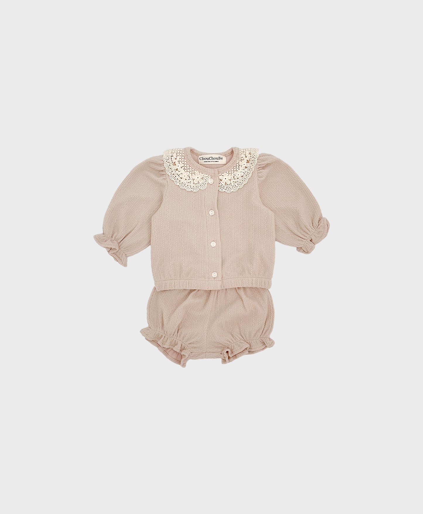 A baby girl's outfit featuring a beige cardigan with a lace collar and ruffled shorts.