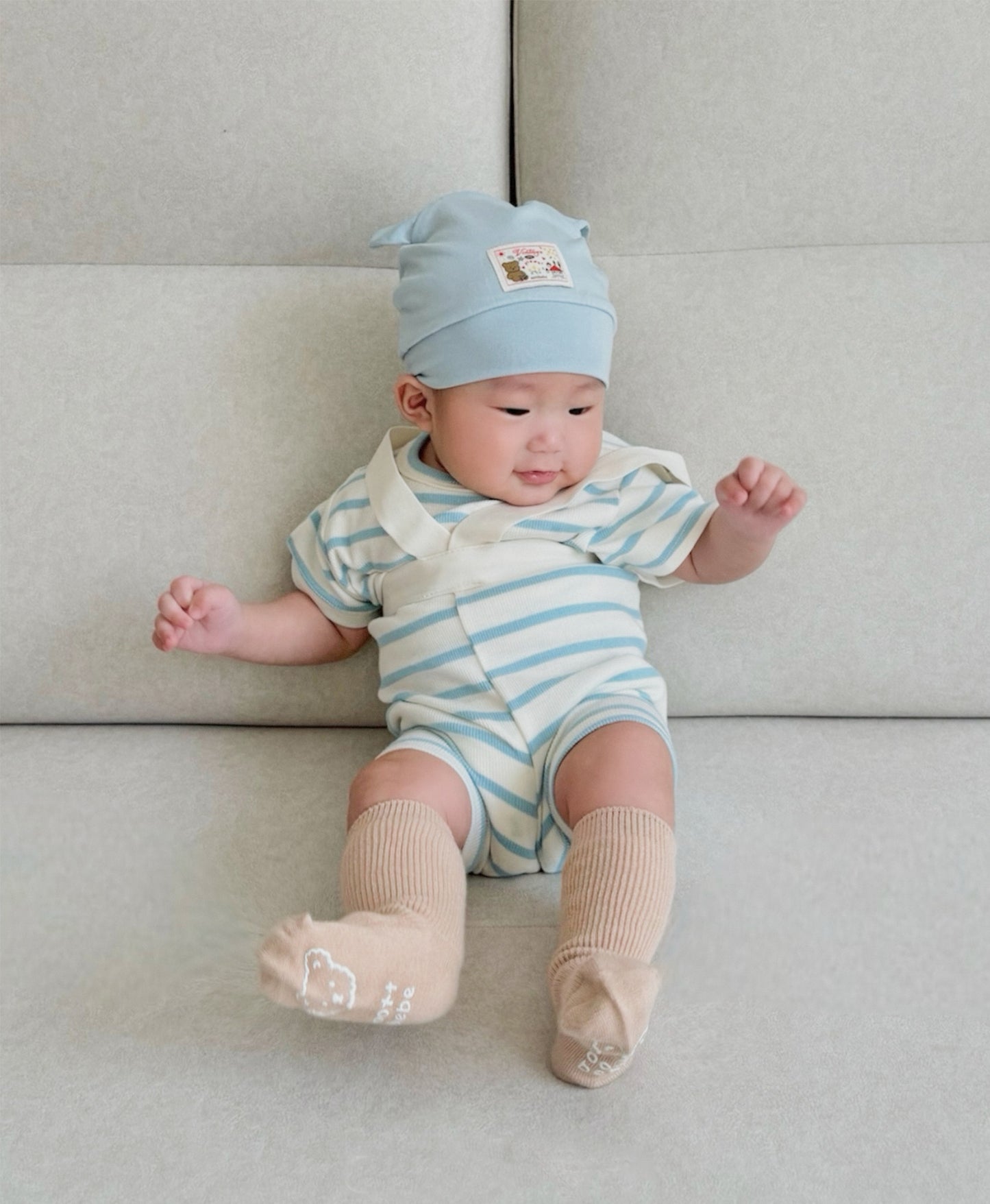 Baby in boys boutique clothing with pastel blue hat sitting