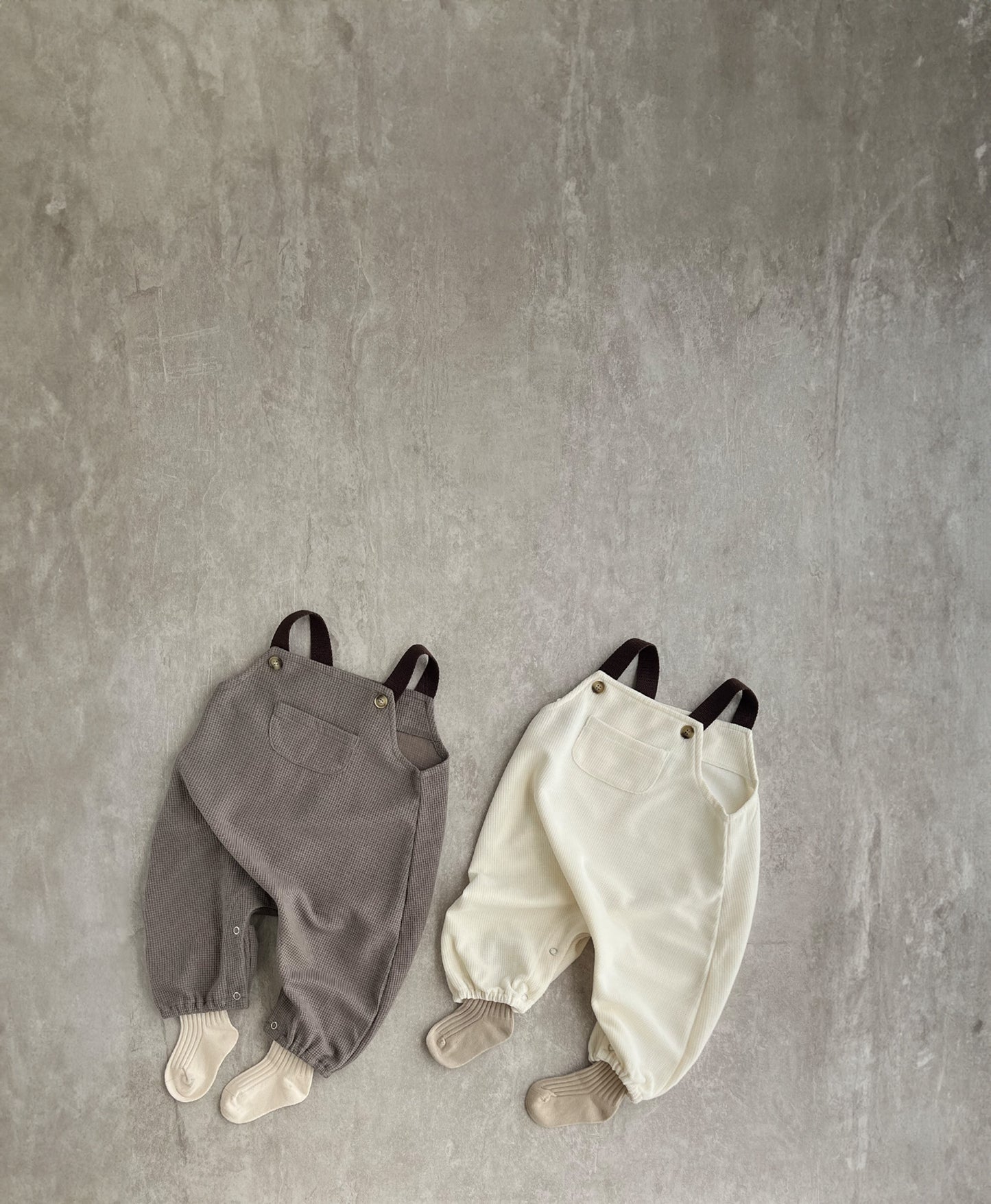 A sleeveless overall with brown straps, perfect for hip baby boys. Features snap buttons for easy dressing. Hipster baby boy clothes.