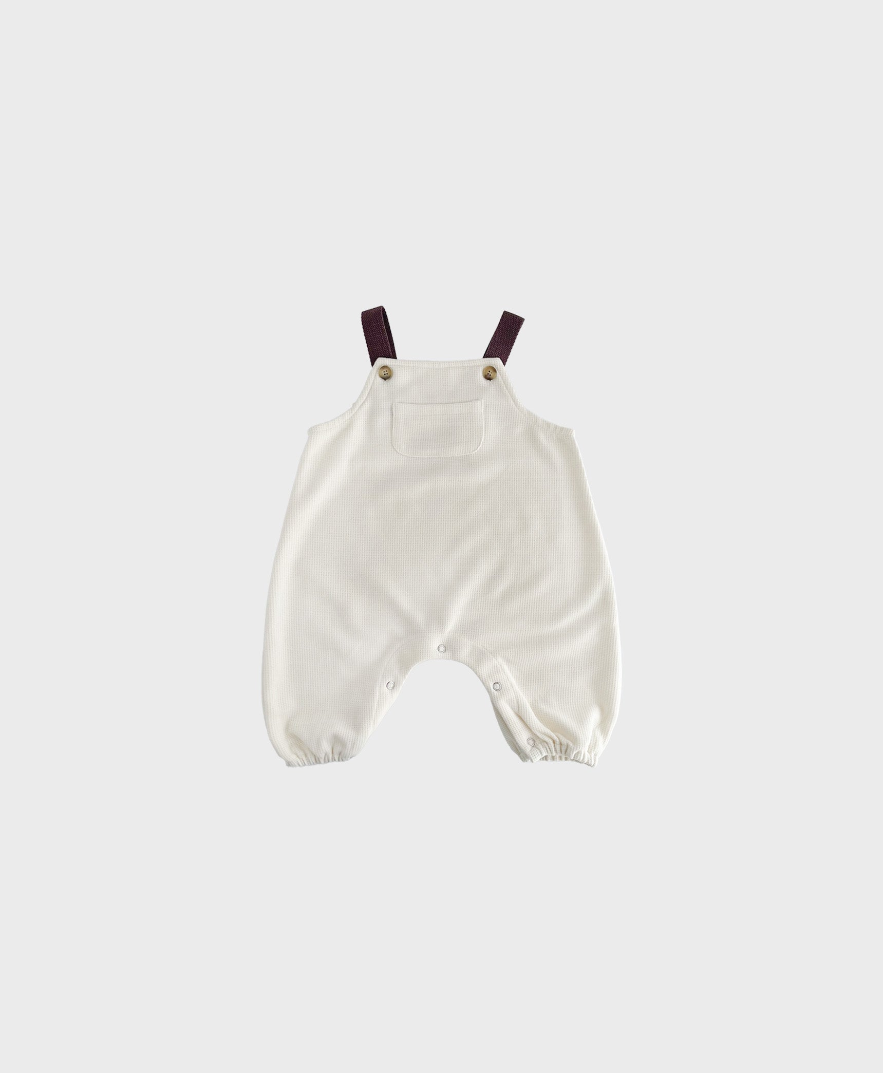 Ivory sleeveless overall with brown straps for hip baby boy with snap buttons.