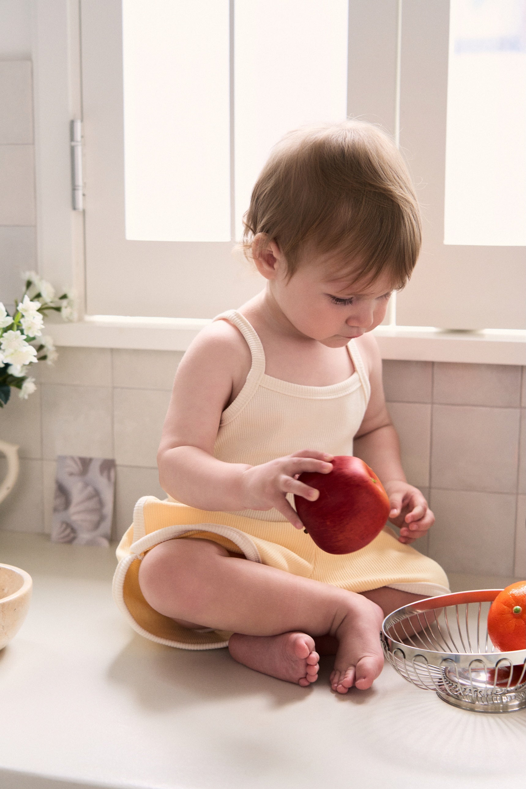 Toddler boy wearing a stylish Korean waffle cardigan set playing with apple