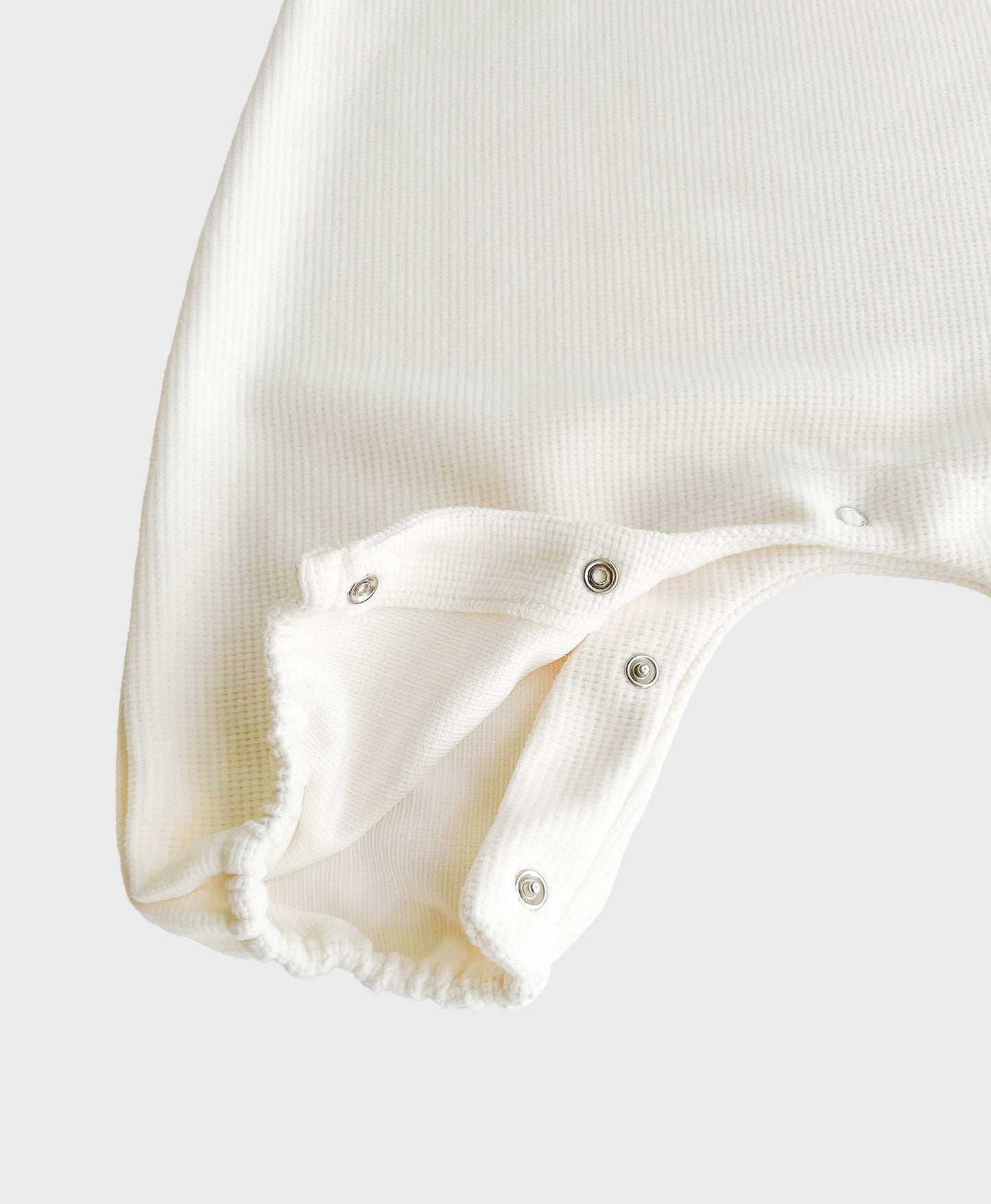 Hipster baby boy clothes: details of Ivory sleeveless overall with easy snap buttons.