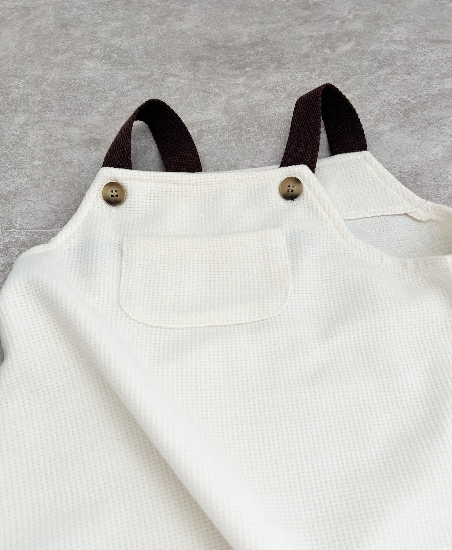 Brown strap sleeveless overall for hip baby boy with snap buttons in clutch..