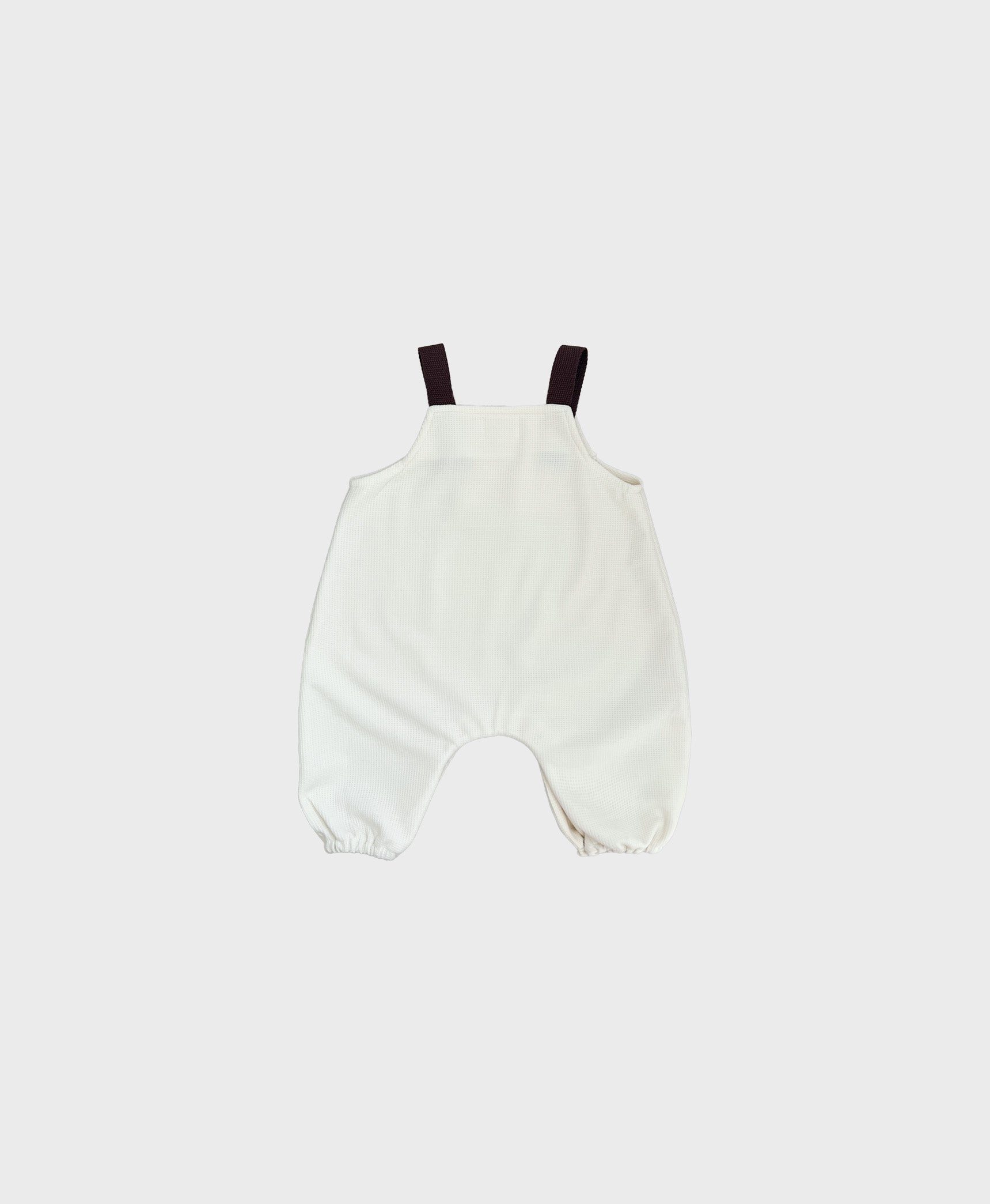 Hipster baby boy clothes: Ivory sleeveless overall with brown straps.