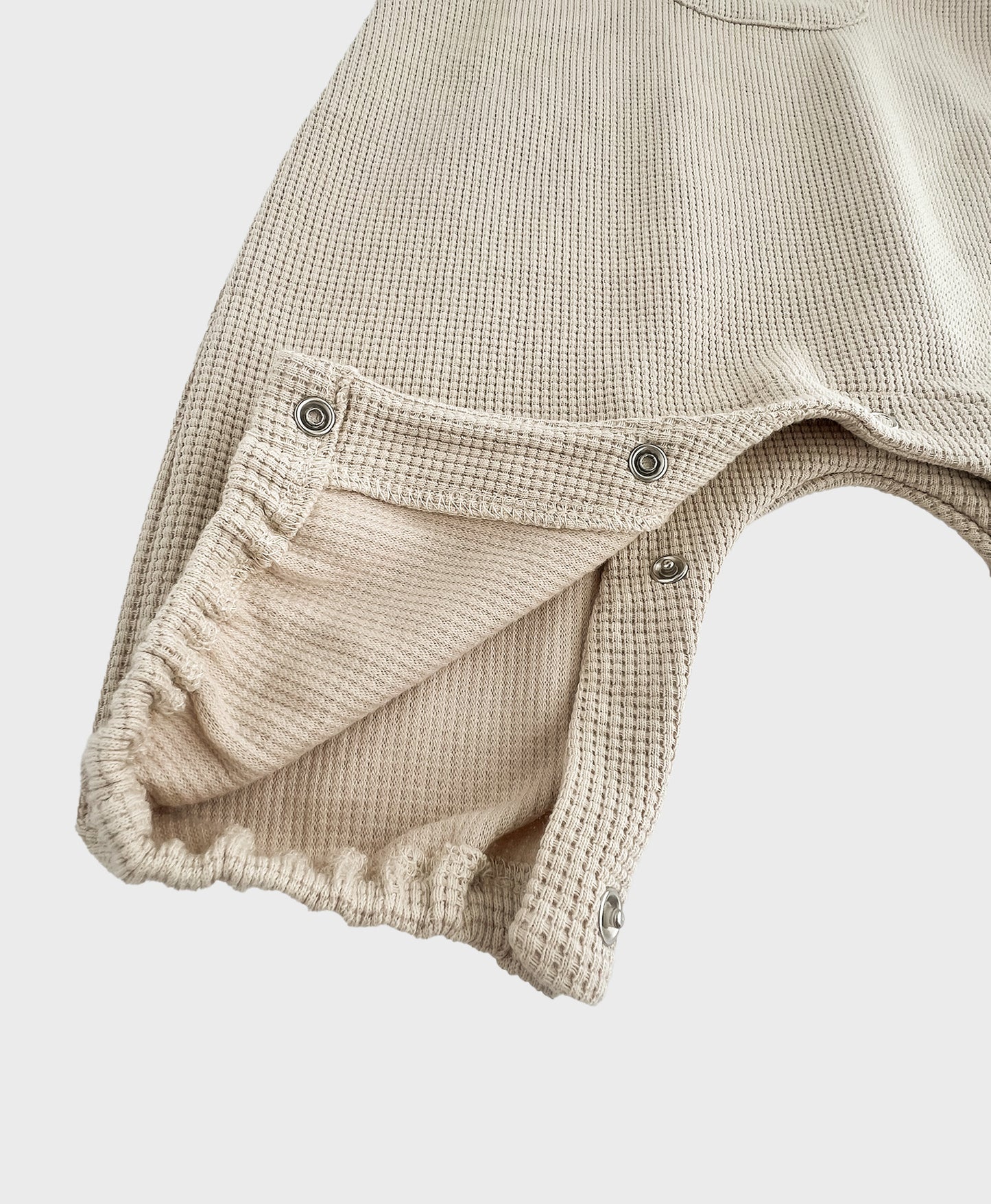 Hipster baby boy clothes: details of beige sleeveless overall with easy snap buttons.