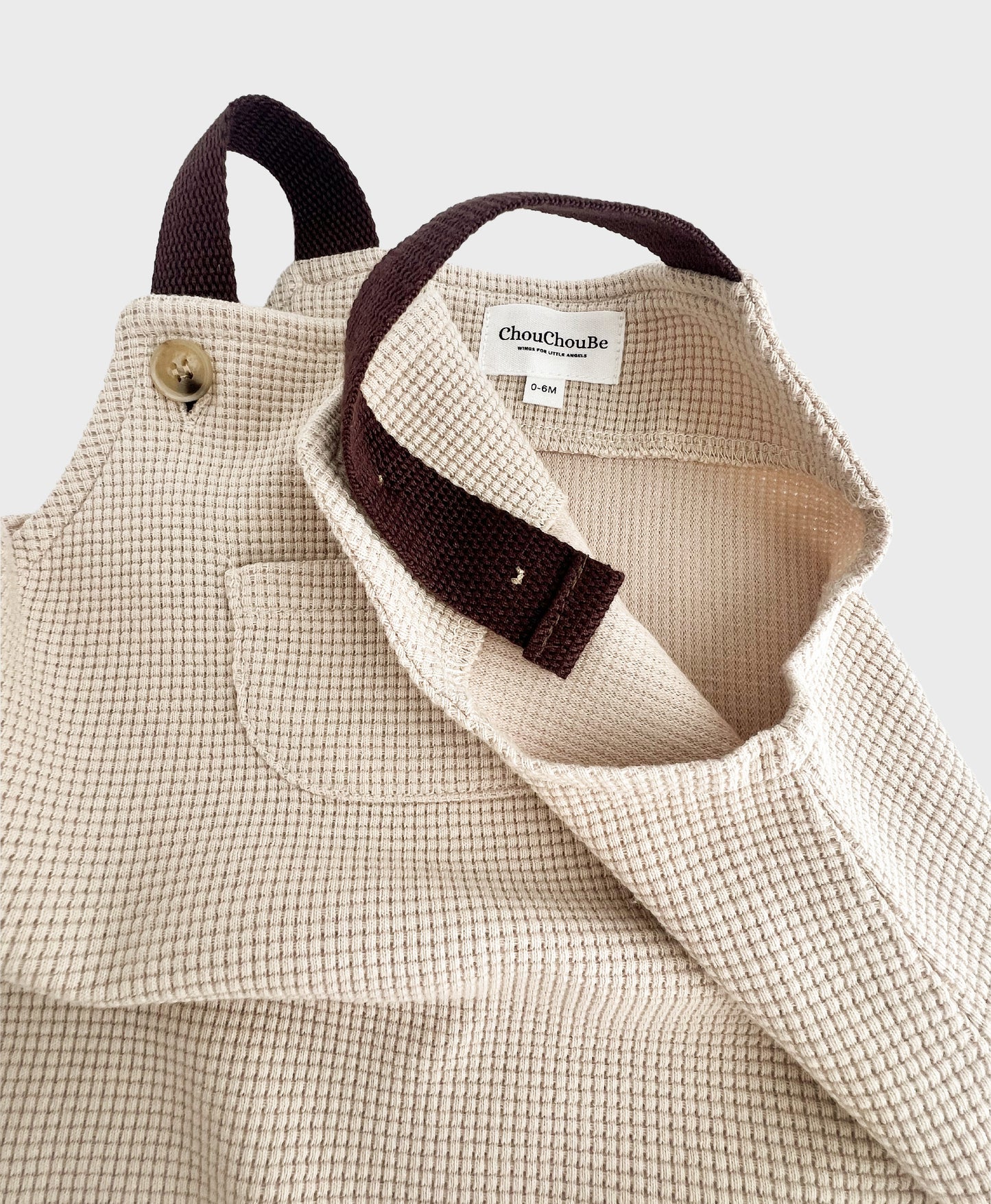 Stylish hip baby boy clothing: Beige sleeveless overall with brown straps.