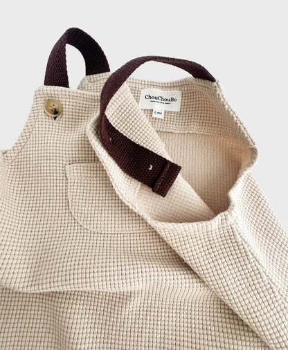 Stylish hip baby boy clothing: Beige sleeveless overall with brown straps.