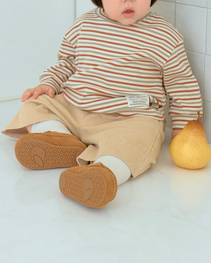 Baby wearing a striped shirt and beige corduroy pants