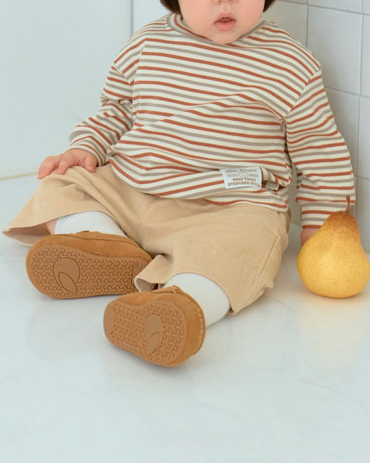Baby wearing a striped shirt and beige corduroy pants