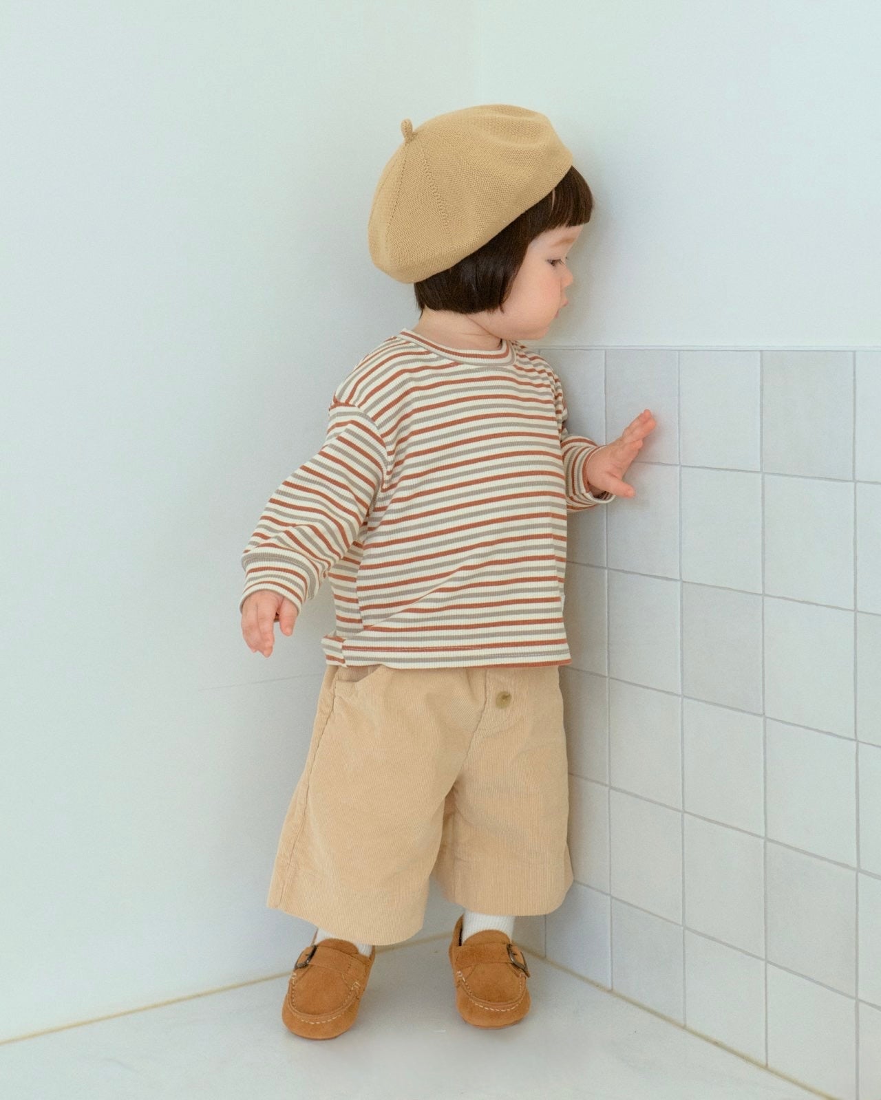 baby toddler wearing a striped shirt and beige pants