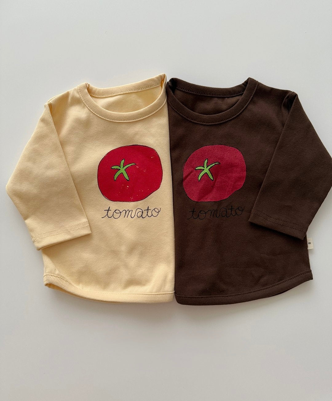 Two long-sleeve shirts, one beige and one brown, with tomato graphics for toddlers and baby