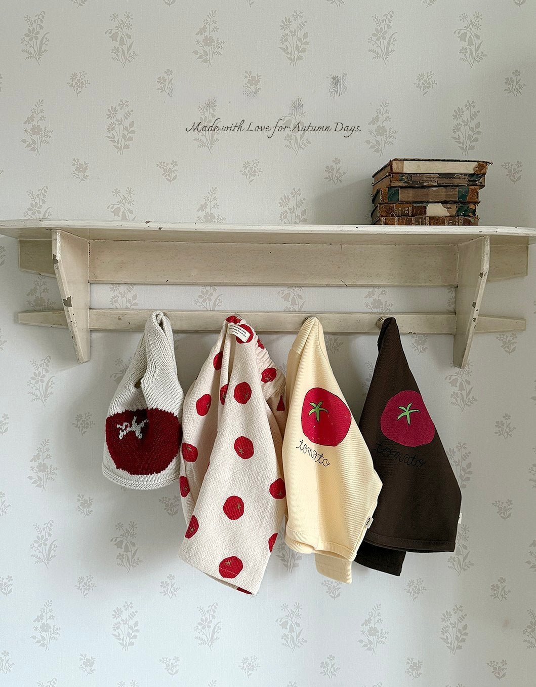 Four embroidered baby and toddler tomato shirts and pants hanging