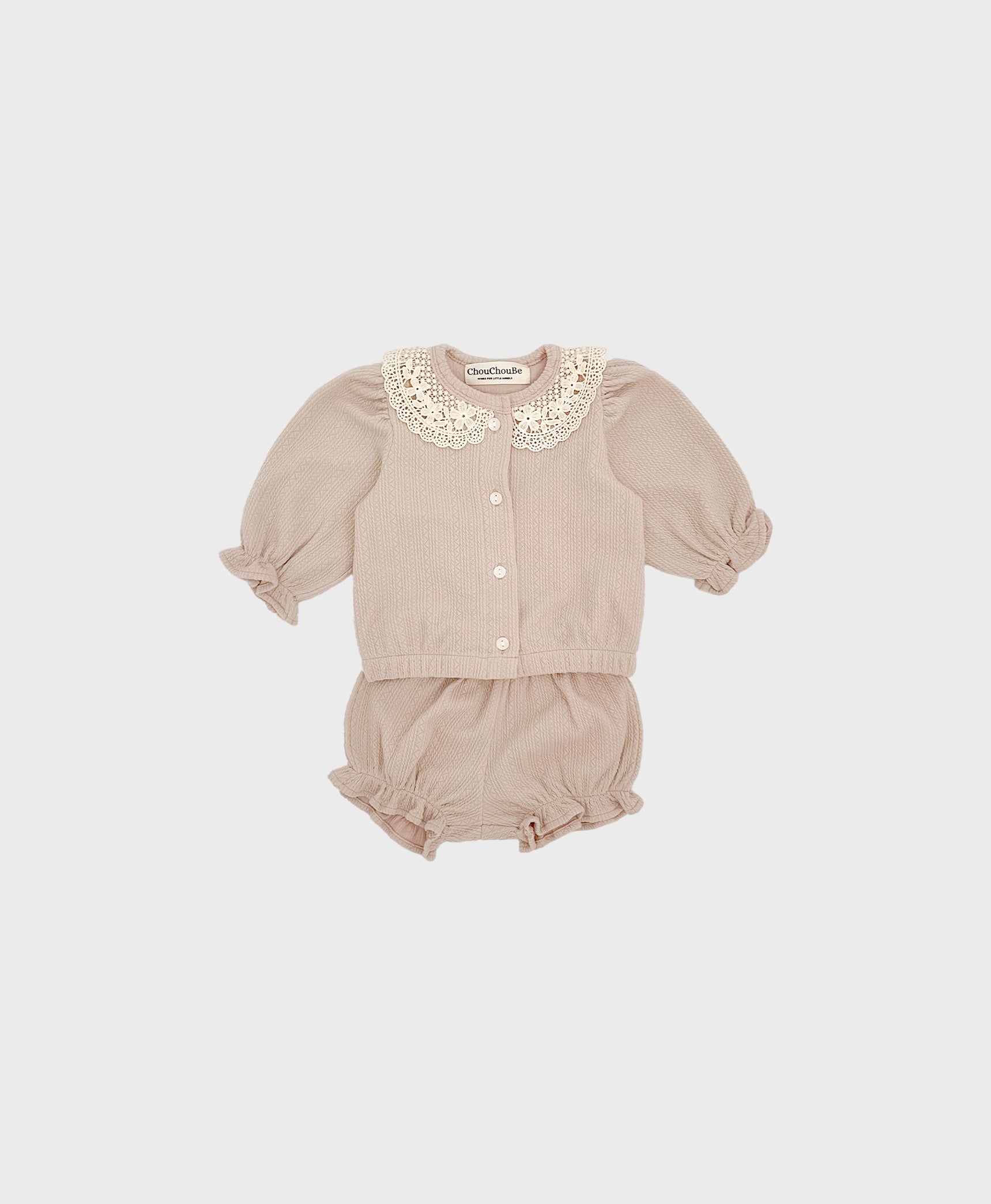 A baby girl's outfit featuring a beige cardigan with a lace collar and ruffled shorts.