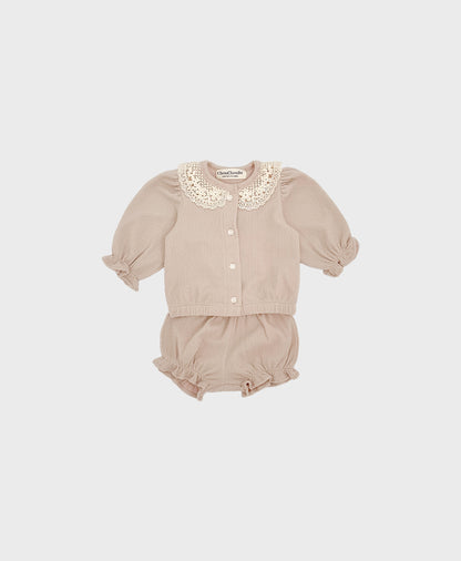 A baby girl's outfit featuring a beige cardigan with a lace collar and ruffled shorts.