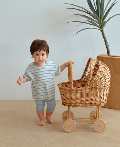 Baby boy in cute toddler boy clothes holding wooden cart