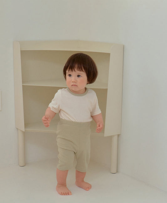 Matching outfits with cotton t-shirts and elastic pants worn by baby and toddler inside a cozy space
