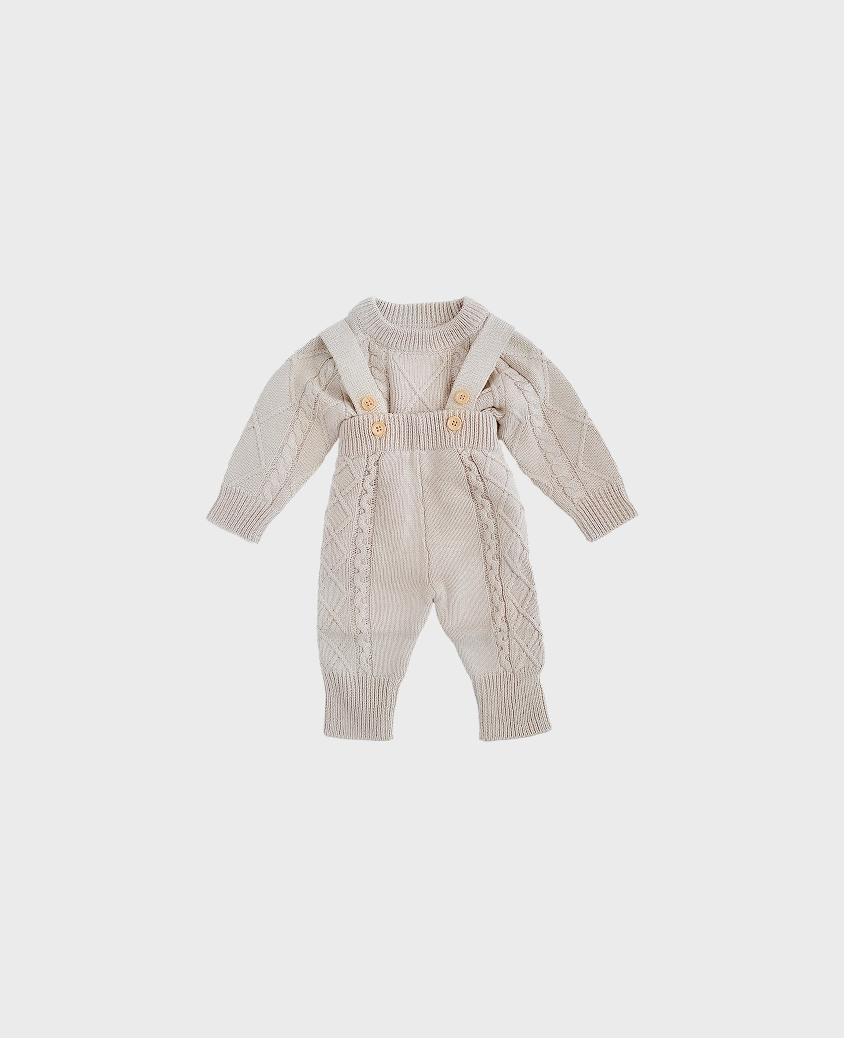 Grey-colored knitted baby onesie with cable-knit patterns and suspenders, laid flat on a plain background.