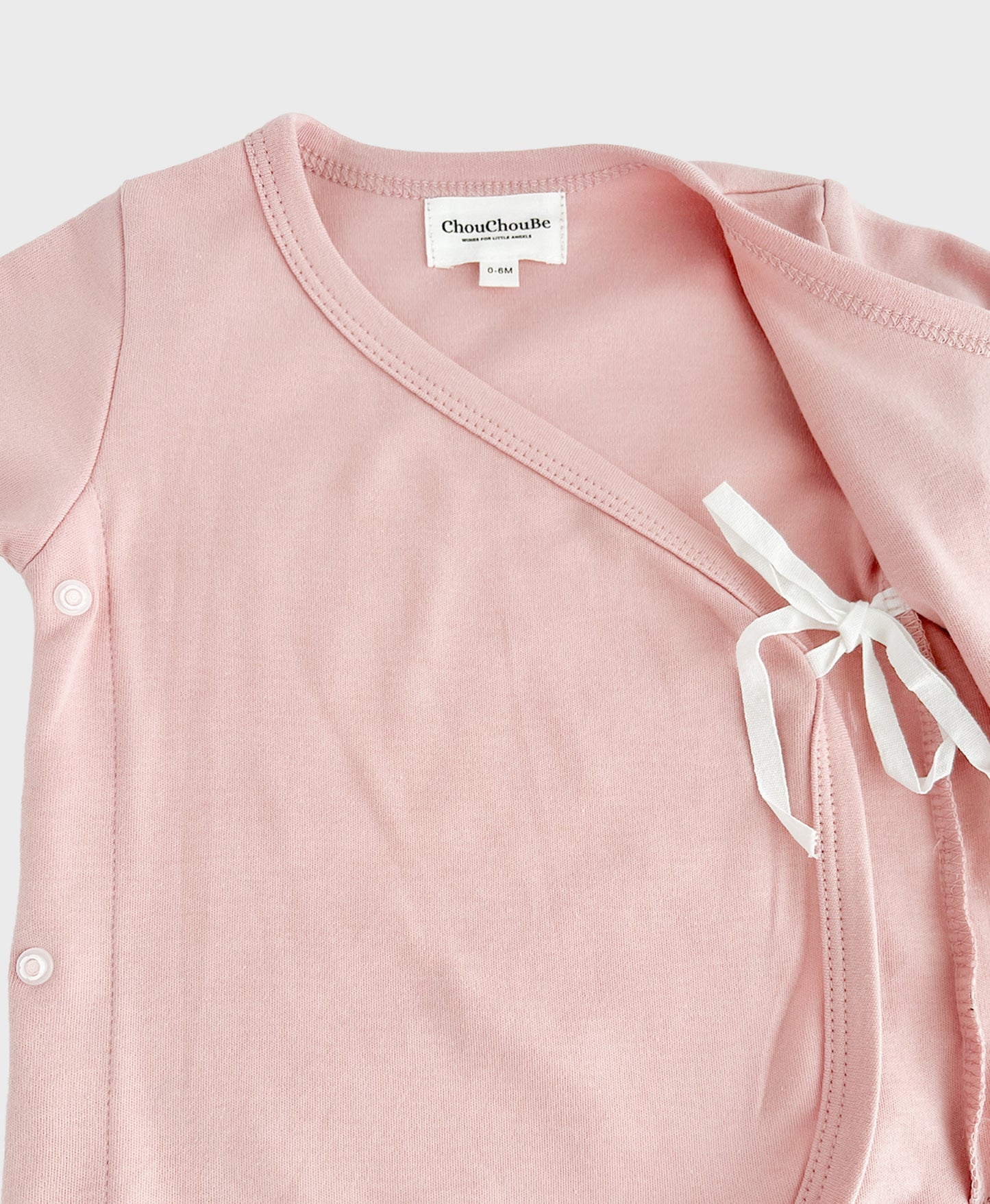 Pink baby newborn outfit set with hat, detailing with straps inside.