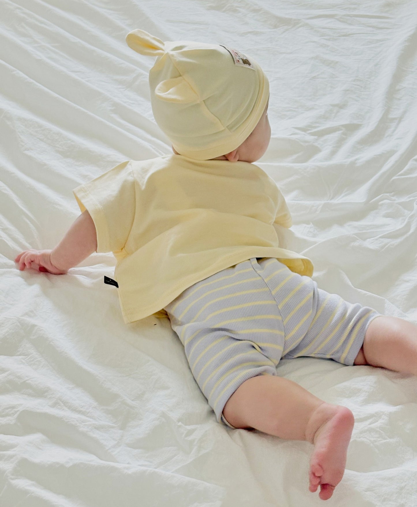 baby wearing soft boys boutique clothing, laying on the bed