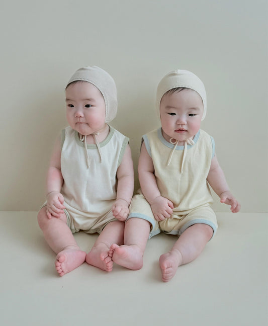 Toddler and baby wearing matching outfits while sitting side by side