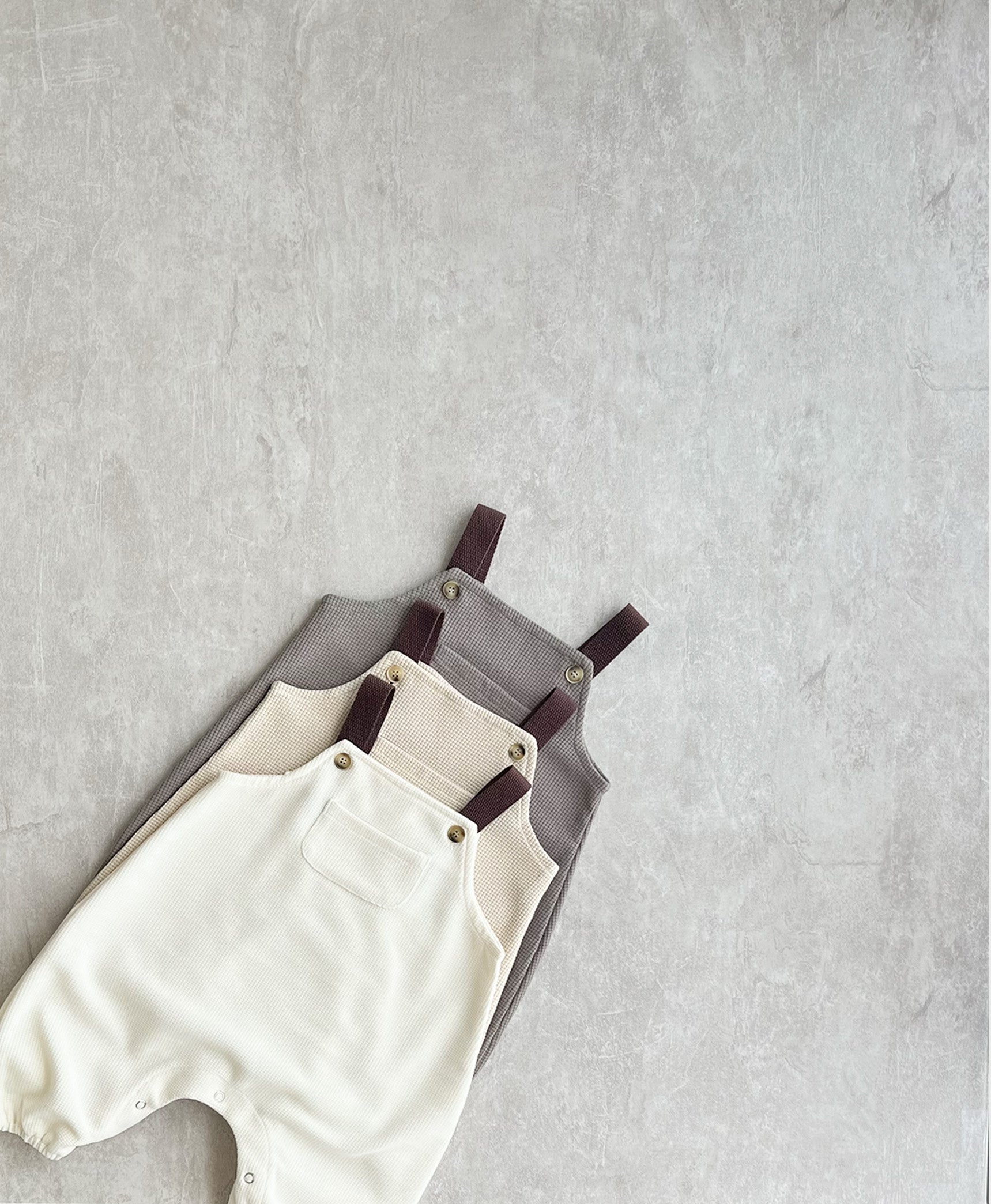 A collection of sleeveless overall with brown straps for hip baby boy with snap buttons.