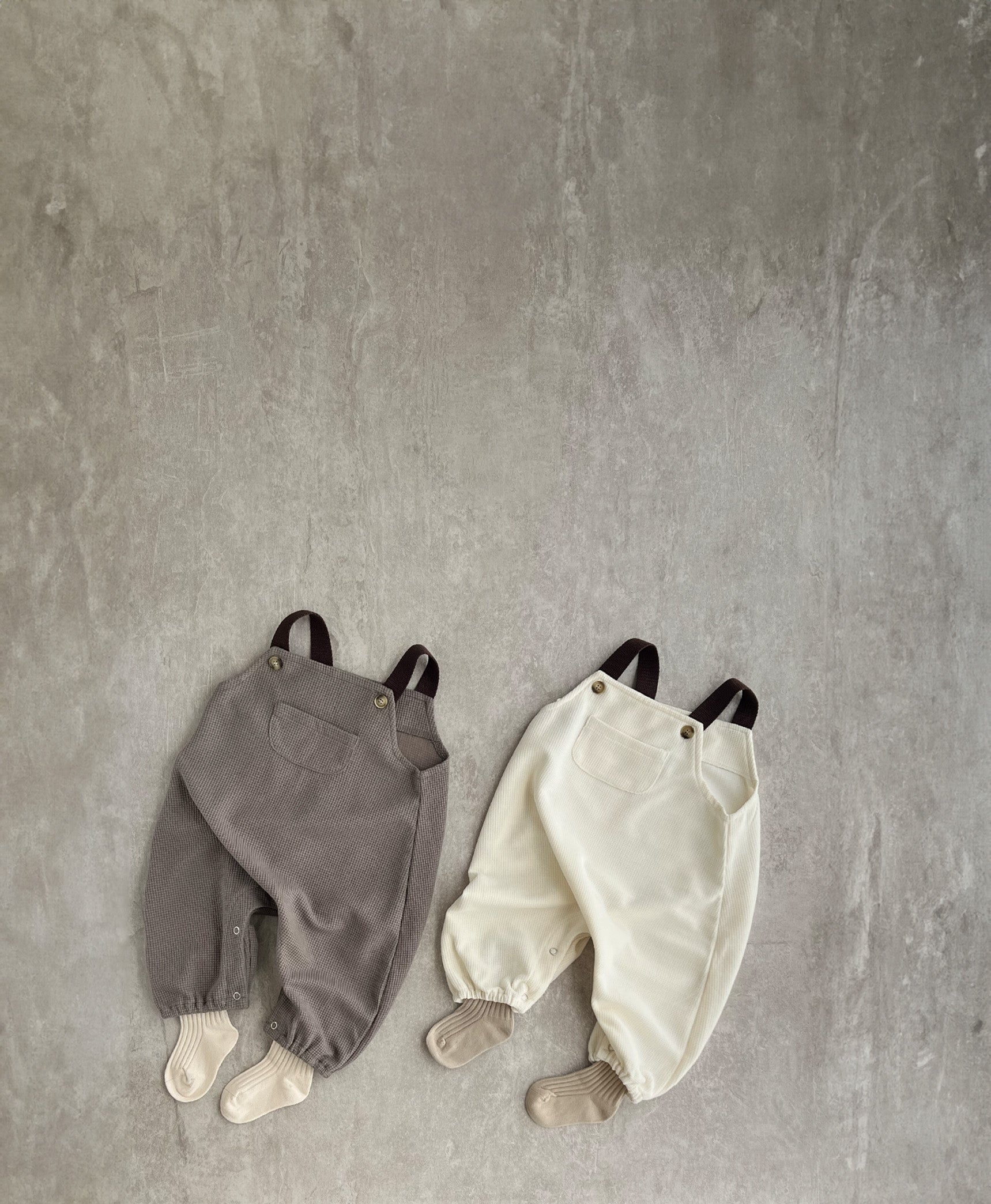 A sleeveless overall with brown straps, perfect for hip baby boys. Features snap buttons for easy dressing. Hipster baby boy clothes.